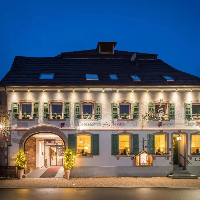 Gasthaus Hotel Adler in Königschaffhausen Traditionelles Restaurant mit beleuchteter Fassade und grünen Fensterläden bei Nacht.