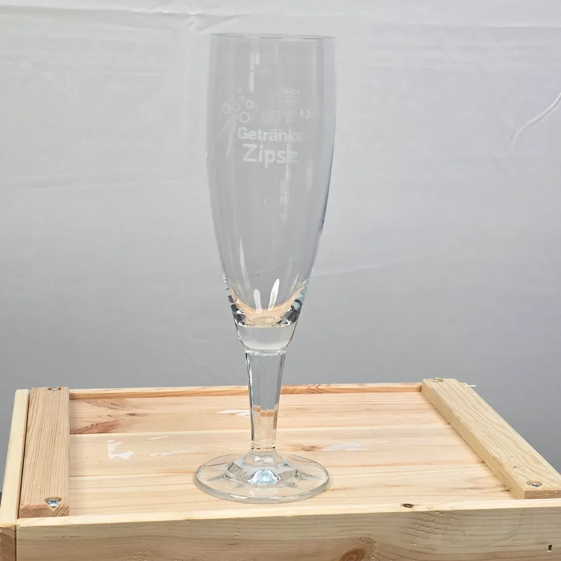 Ein elegantes Bierglas auf einer Holzbox, graviert und transparent.