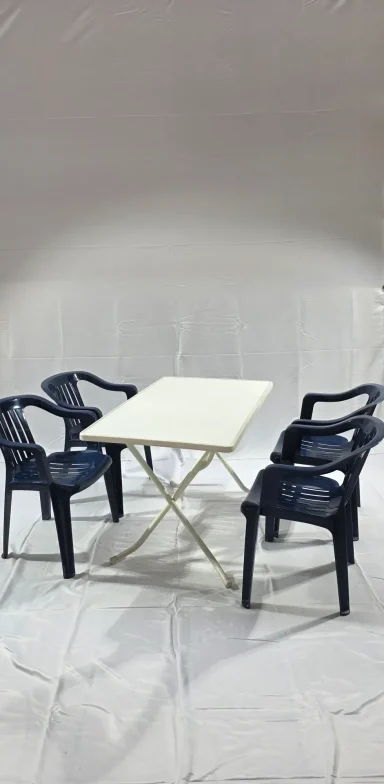 Ein Tisch mit vier blauen Plastikstühlen auf einem hellen Hintergrund.