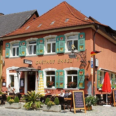 Hotel Engel in Endingen Bunt dekoriertes Restaurant mit Außensitzplätzen und begrünten Fenstern.