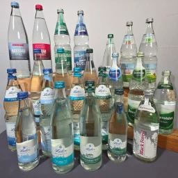 Vielfältige Wassermarken in Glasflaschen mit verschiedenen Designs und Etiketten.