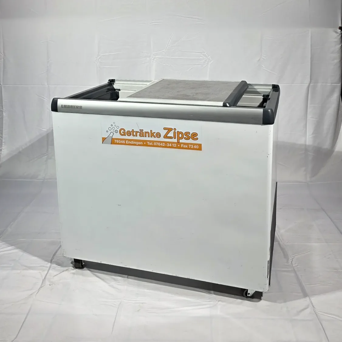 Weiße, rechteckige Kühltrruhe mit einem Markenaufdruck auf der Frontseite.