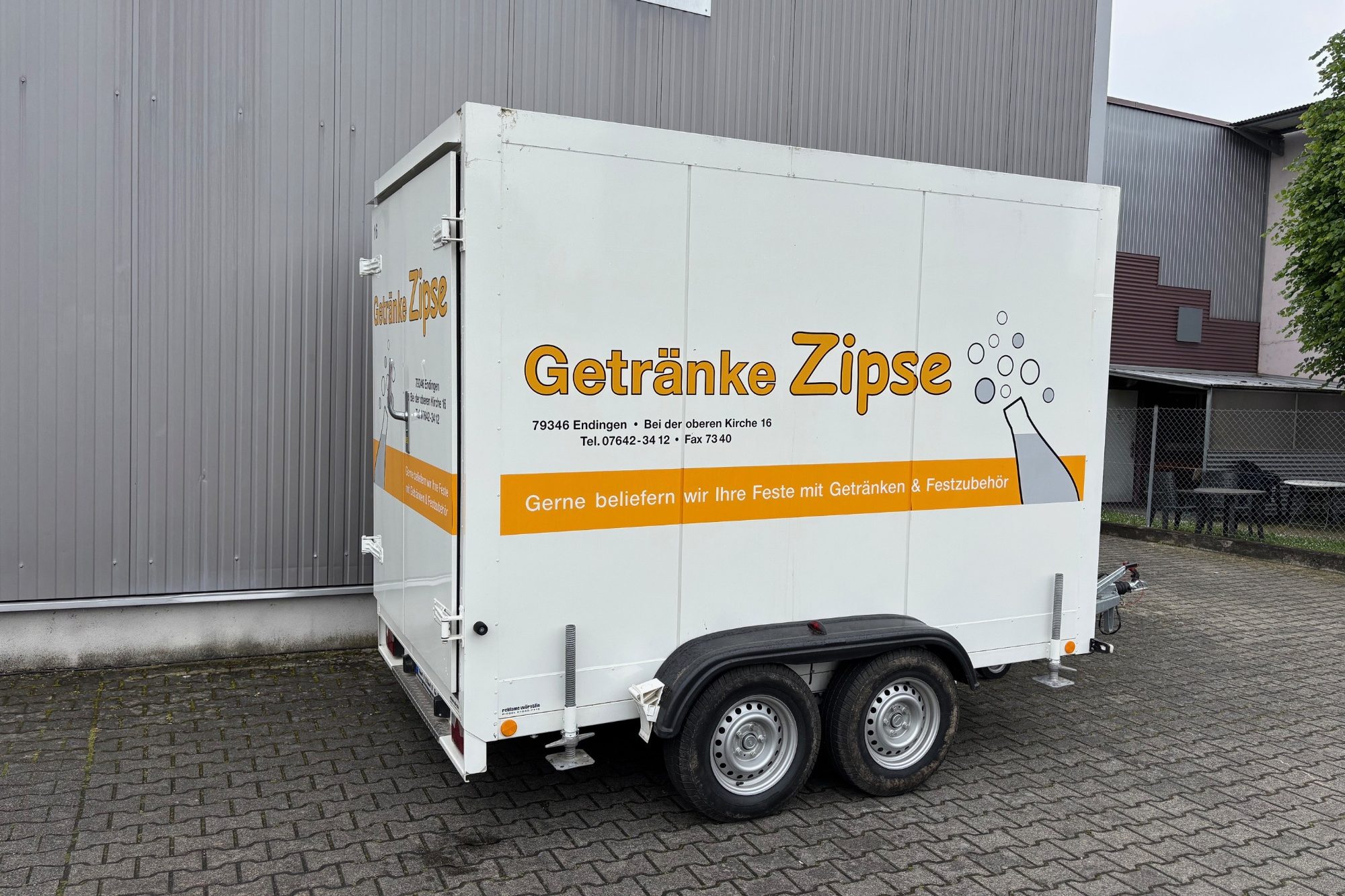 Kühlanhänger mit der Aufschrift "Getränke Zipse" und einem Glas mit Getränken.