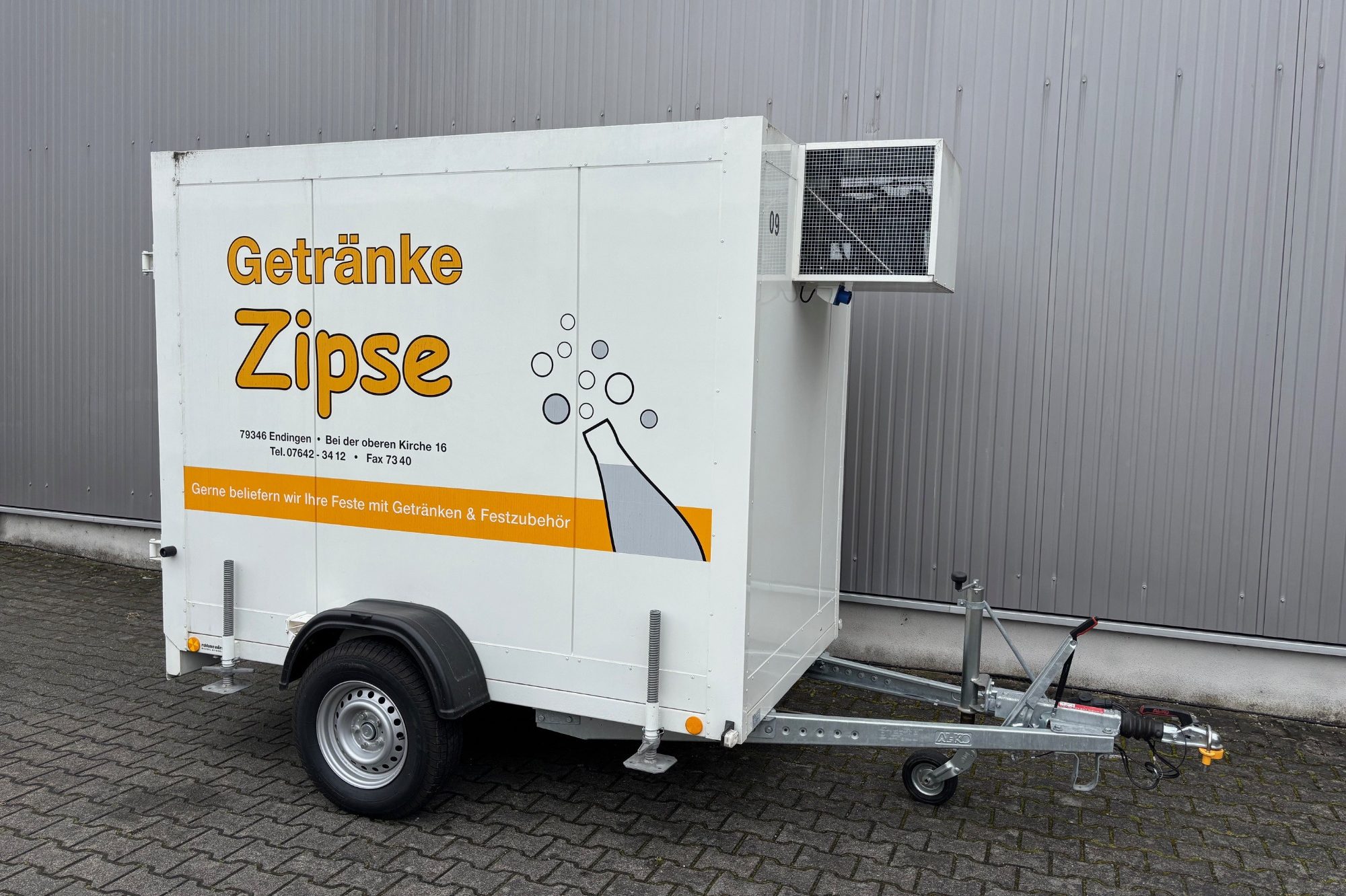 Kühlanhänger mit der Aufschrift "Getränke Zipse" und einem Glas mit Getränken.