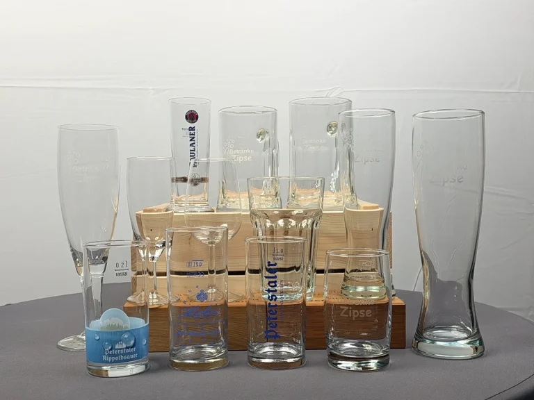 Verschiedene Gläser auf einem Holzuntergrund, leere und mit unterschiedlichen Designs.