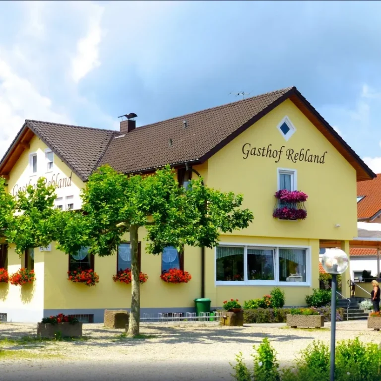 Gästehaus mit gelber Fassade, Blumenkästen und nettem Eingangsbereich.