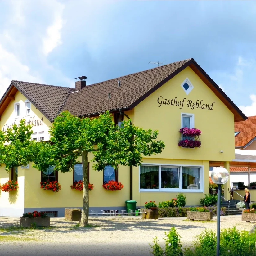 Gasthof Rebland in Eichstetten Gästehaus mit gelber Fassade, blühenden Kästen und Blumen vor dem Fenster.