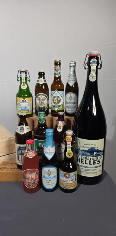 Verschiedene Bierflaschen und -dosen in unterschiedlichen Größen und Marken.