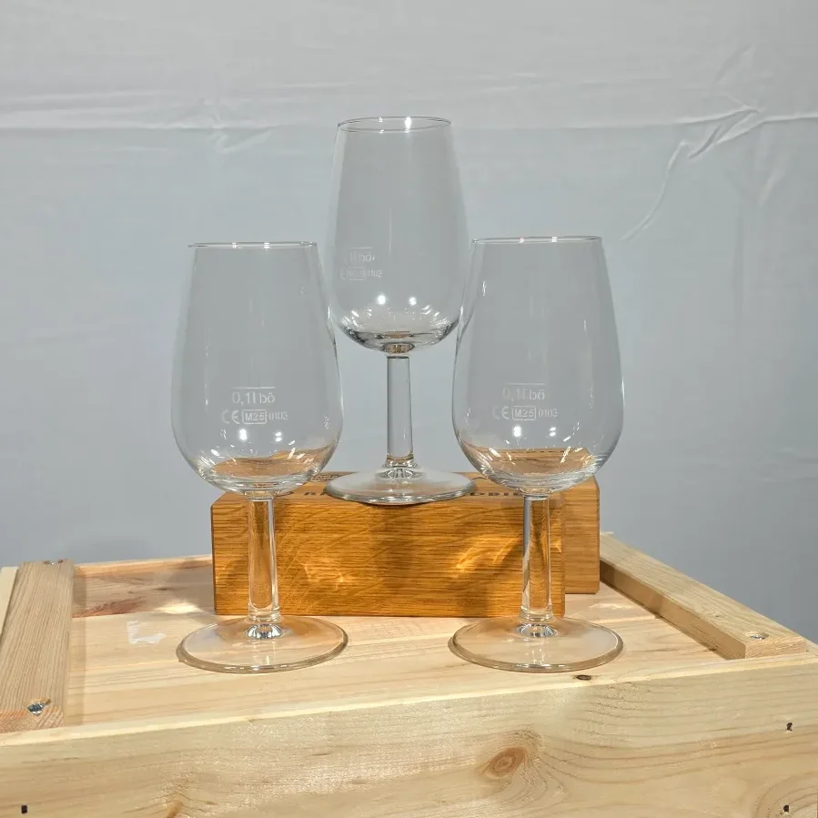 Drei Weingläser in verschiedenen Höhen stehen auf einem Holzblock.