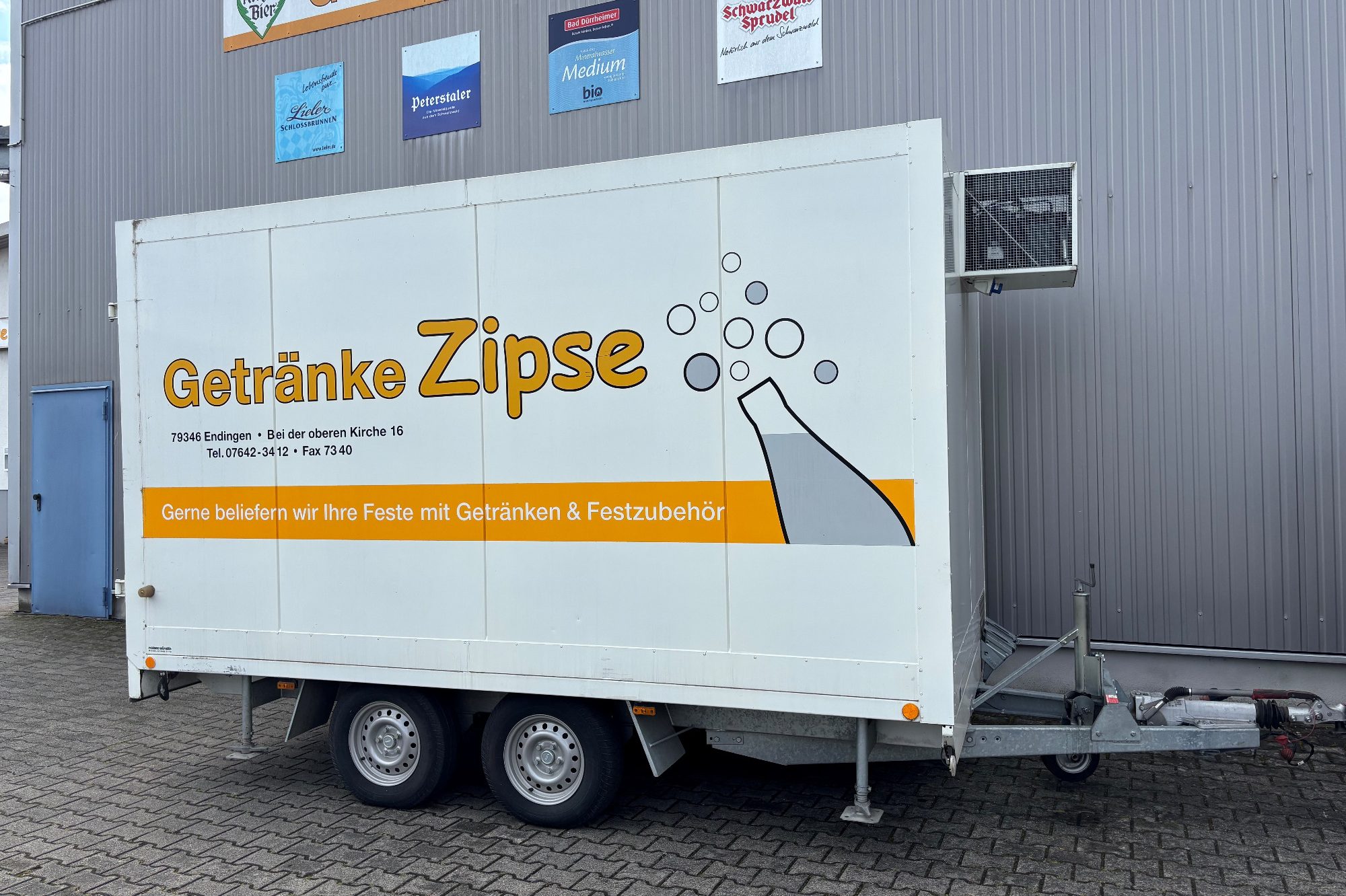 Kühlanhänger mit der Aufschrift "Getränke Zipse" und einem Glas mit Getränken.