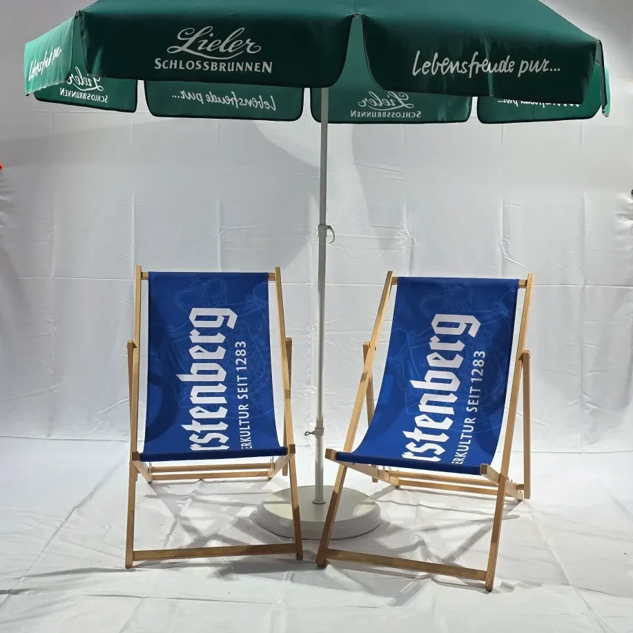 Zwei Liegestühle mit blauen Bezug und Sonnenschirm mit Werbung im Hintergrund.